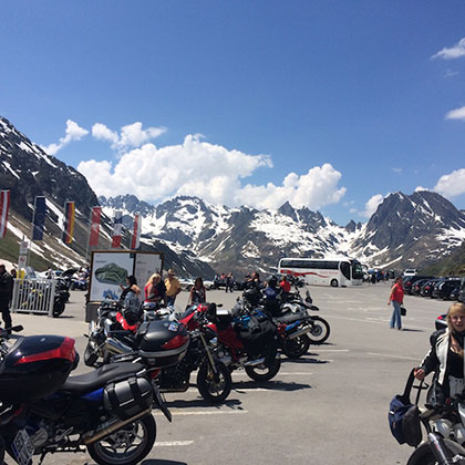 auf Parkplatz abgestellte Motorräder vor Alpenpanorama